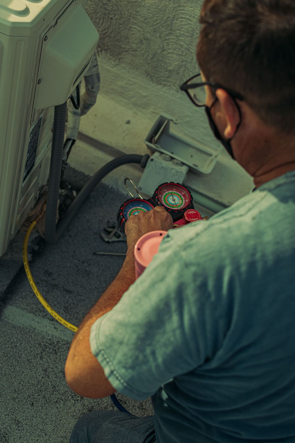 Technician reading refrigerant gauges while commissioning an air conditioning install